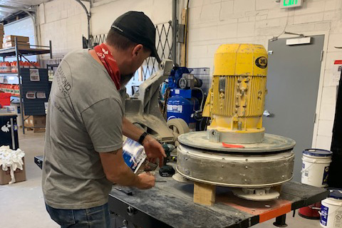 image of a man working on a concrete grinder and vacuum
